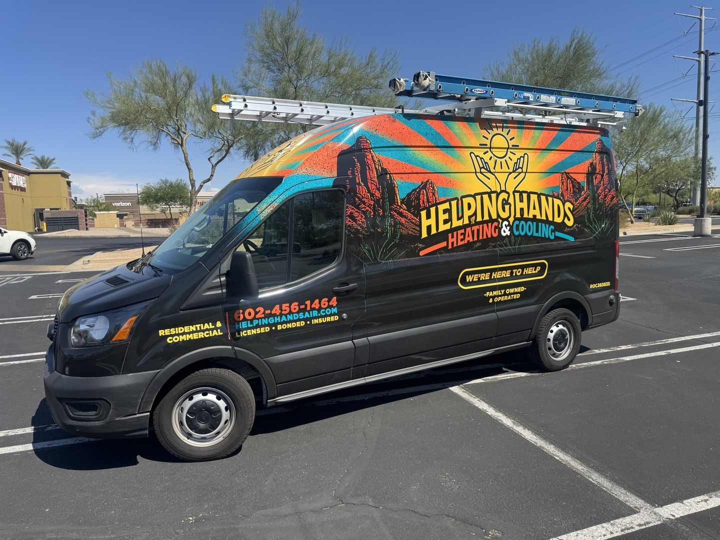 The Helping Hands Heating & Cooling van with the desert sunburst wrap parked at a job